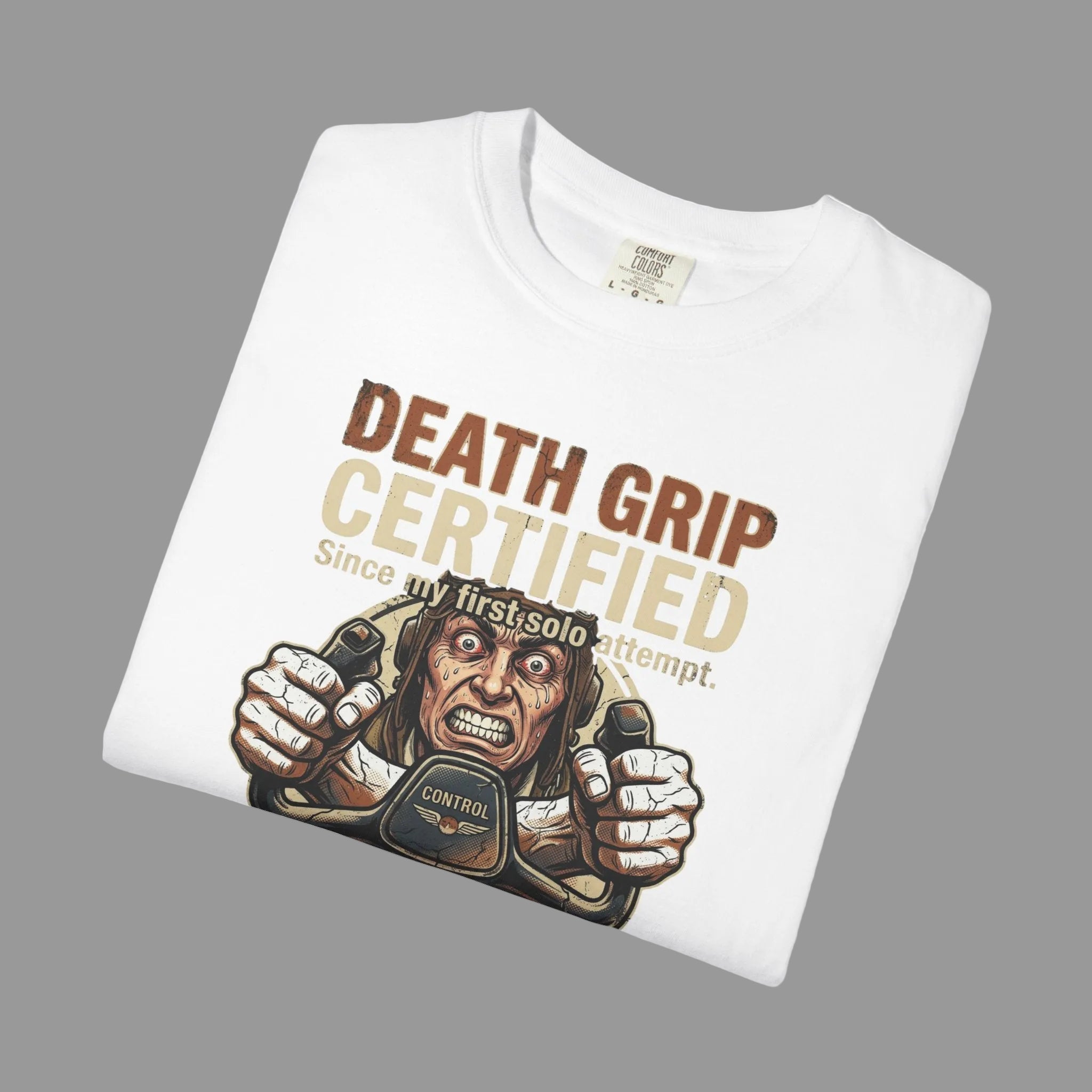 Folded white t-shirt with graphic design and text 'Death Grip Certified' on a grey background