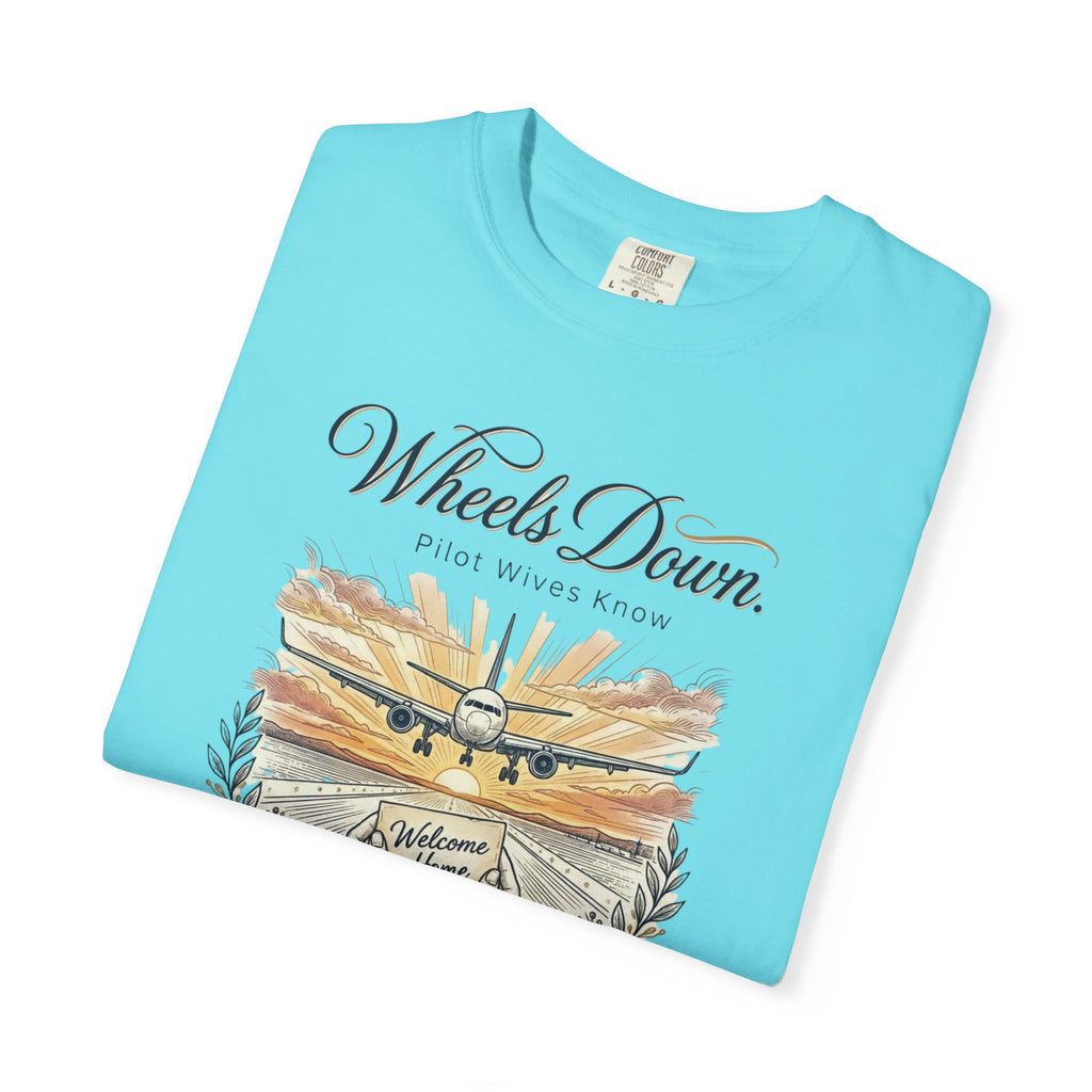 Folded light blue t-shirt with airplane graphic and text on a white background