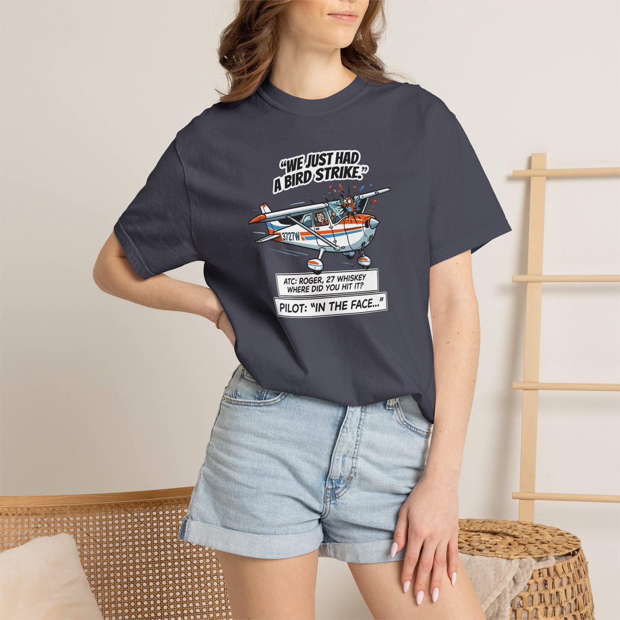 Person wearing a navy blue t-shirt with a graphic design and text, standing against a neutral background.